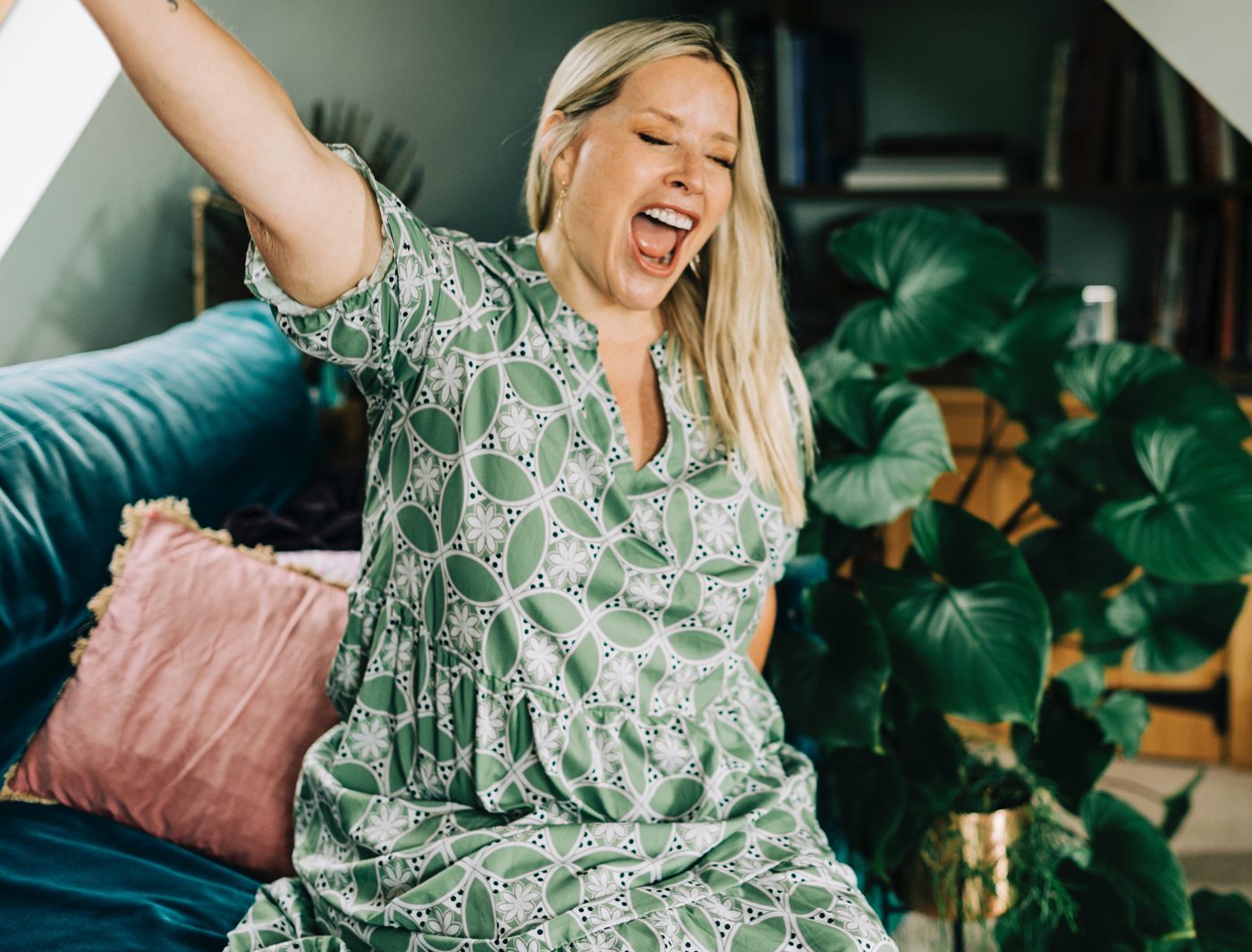 Juliette laughing on a sofa, arm stretched up
