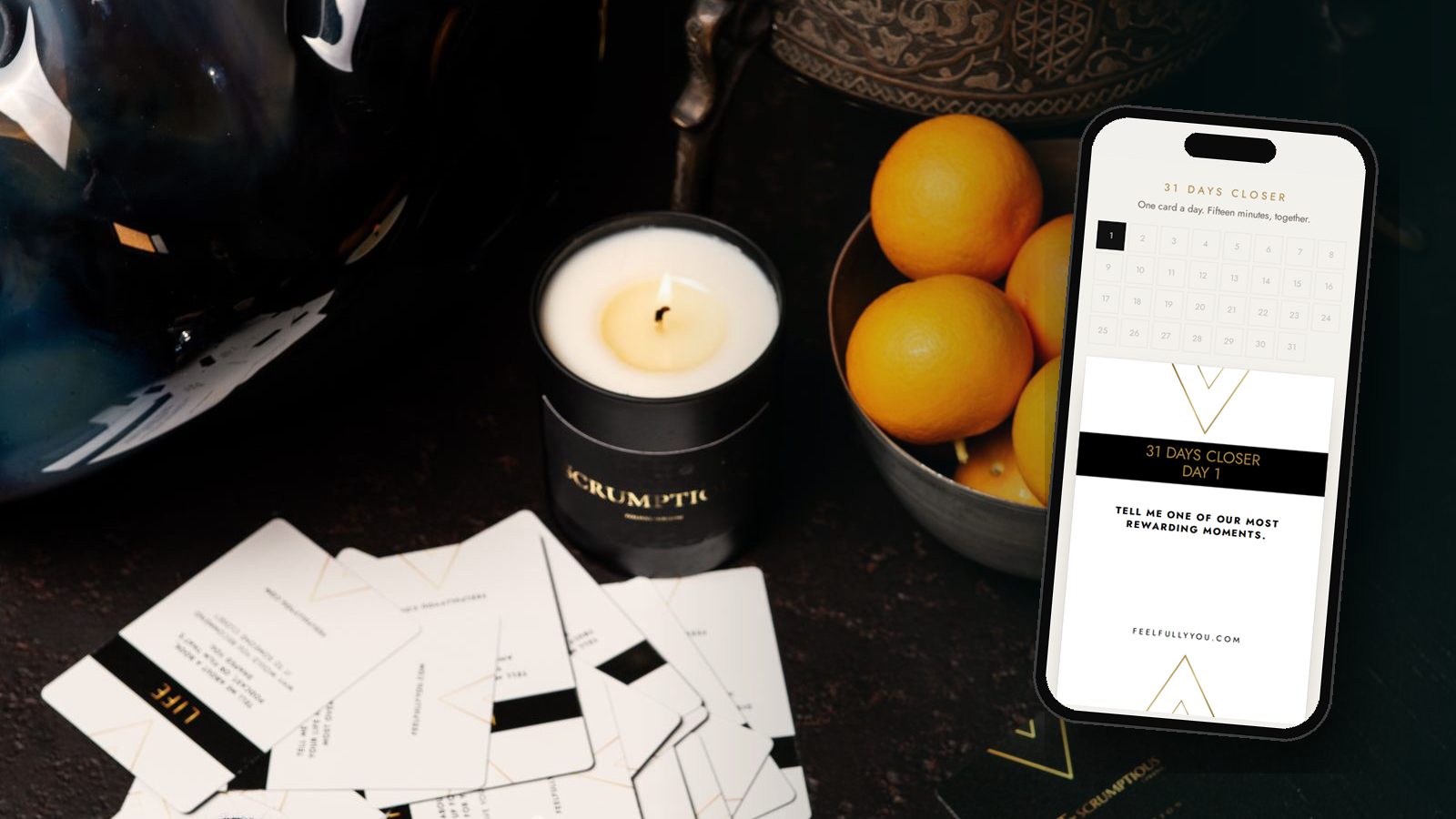 31 Days Closer on a phone, beside the Intimacy and Communication Cards, a candle and a bowl of oranges