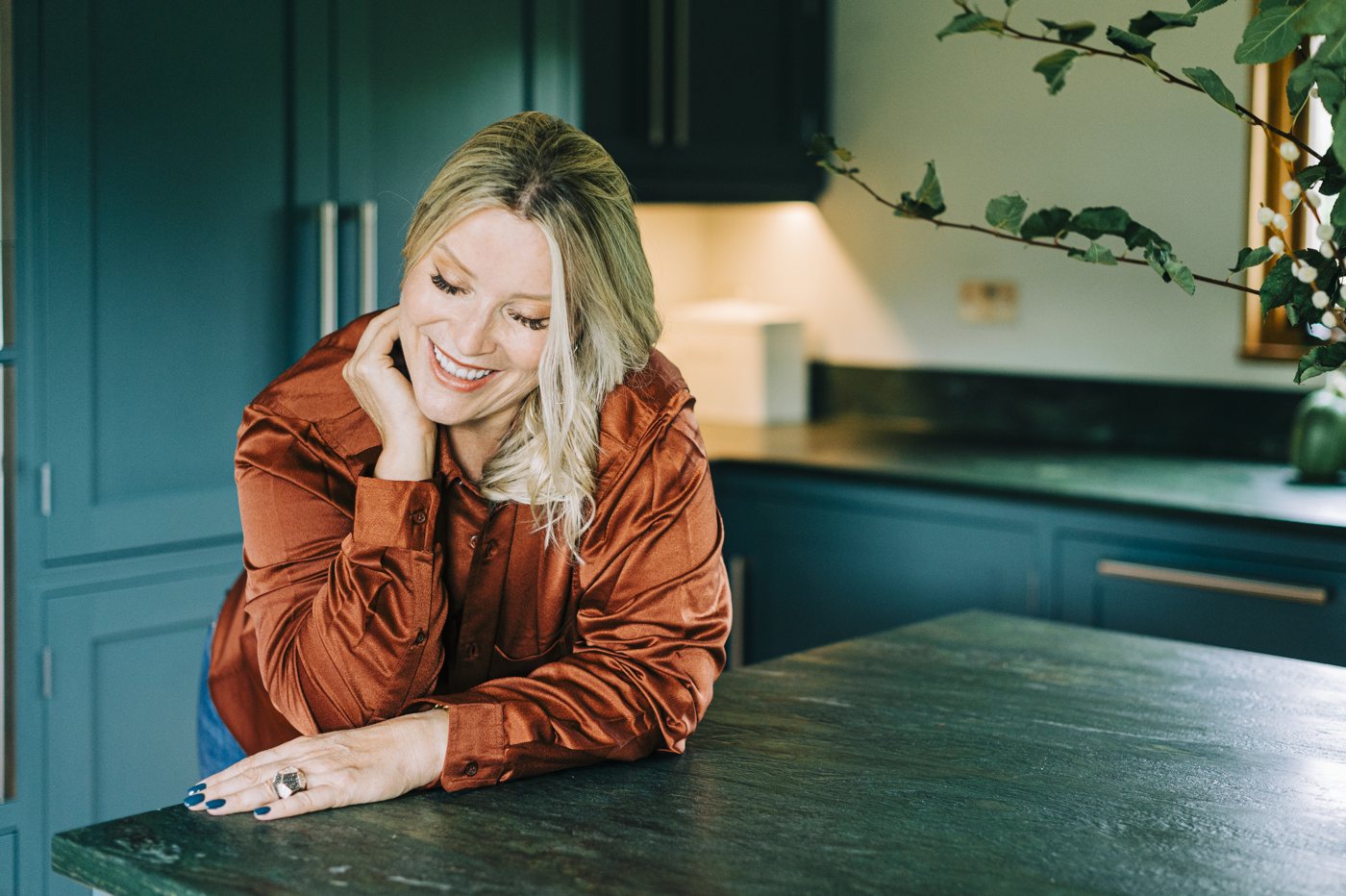 Juliette leaning on a kitchen table, chin resting on her hand, smiling