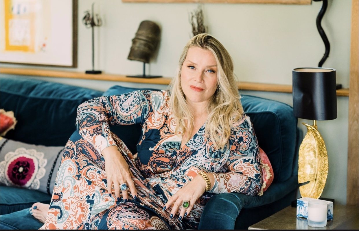 Juliette relaxing on a sofa in a patterned outfit, smiling