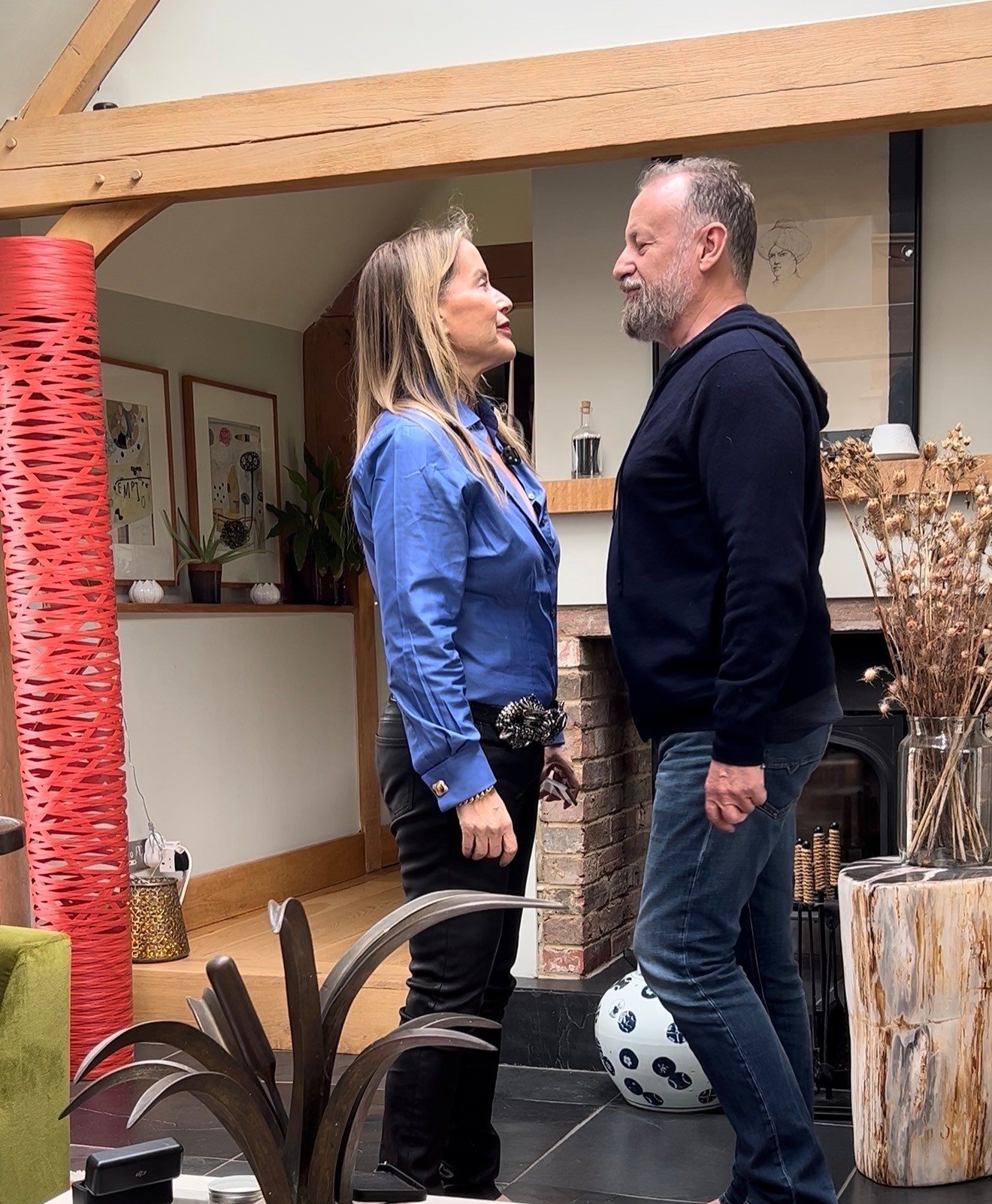 Juliette and her fiancé Alex standing face to face in their home, looking at each other