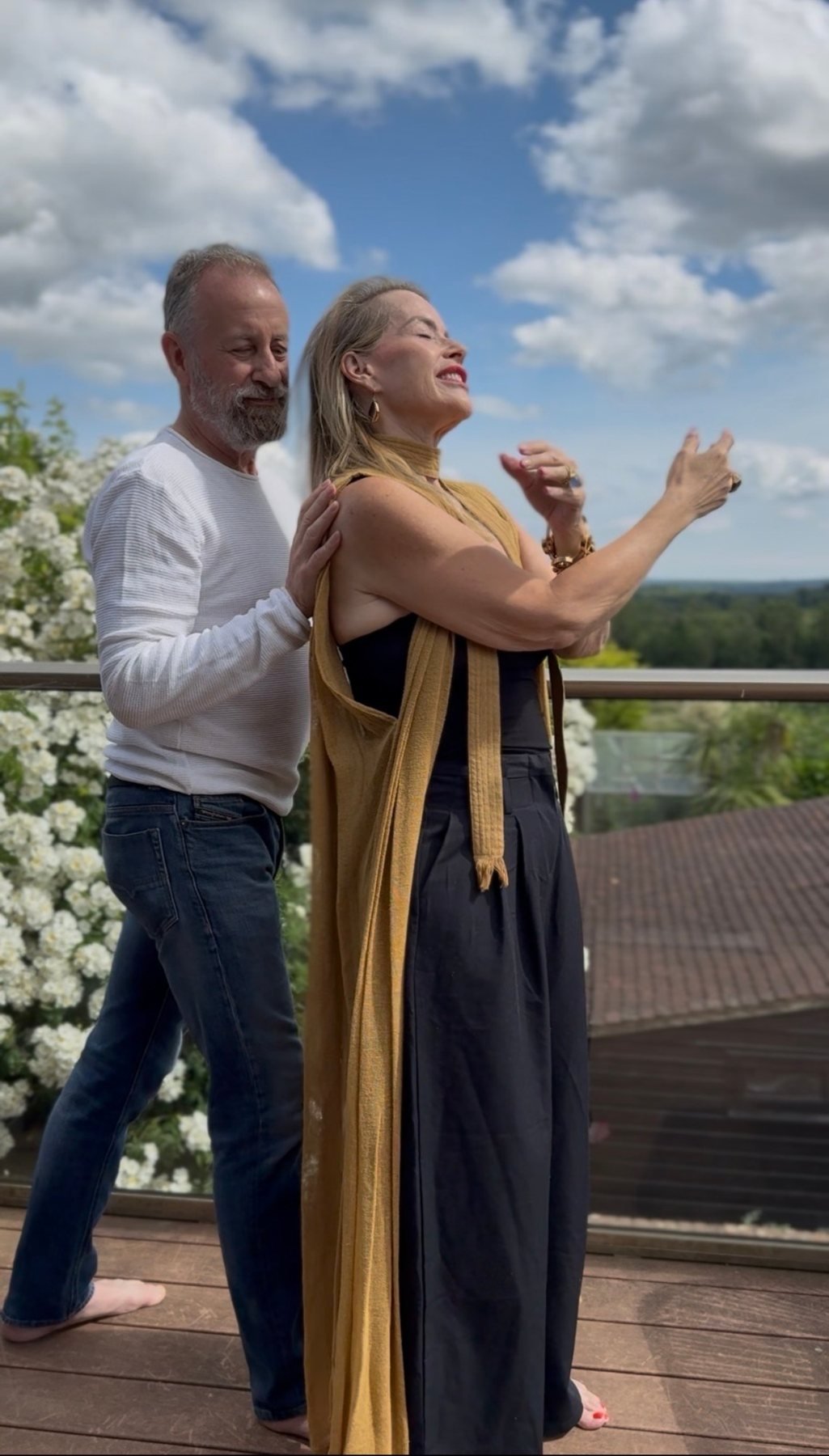 Juliette and Alex on a sunny terrace, Juliette in a long scarf with her arms open