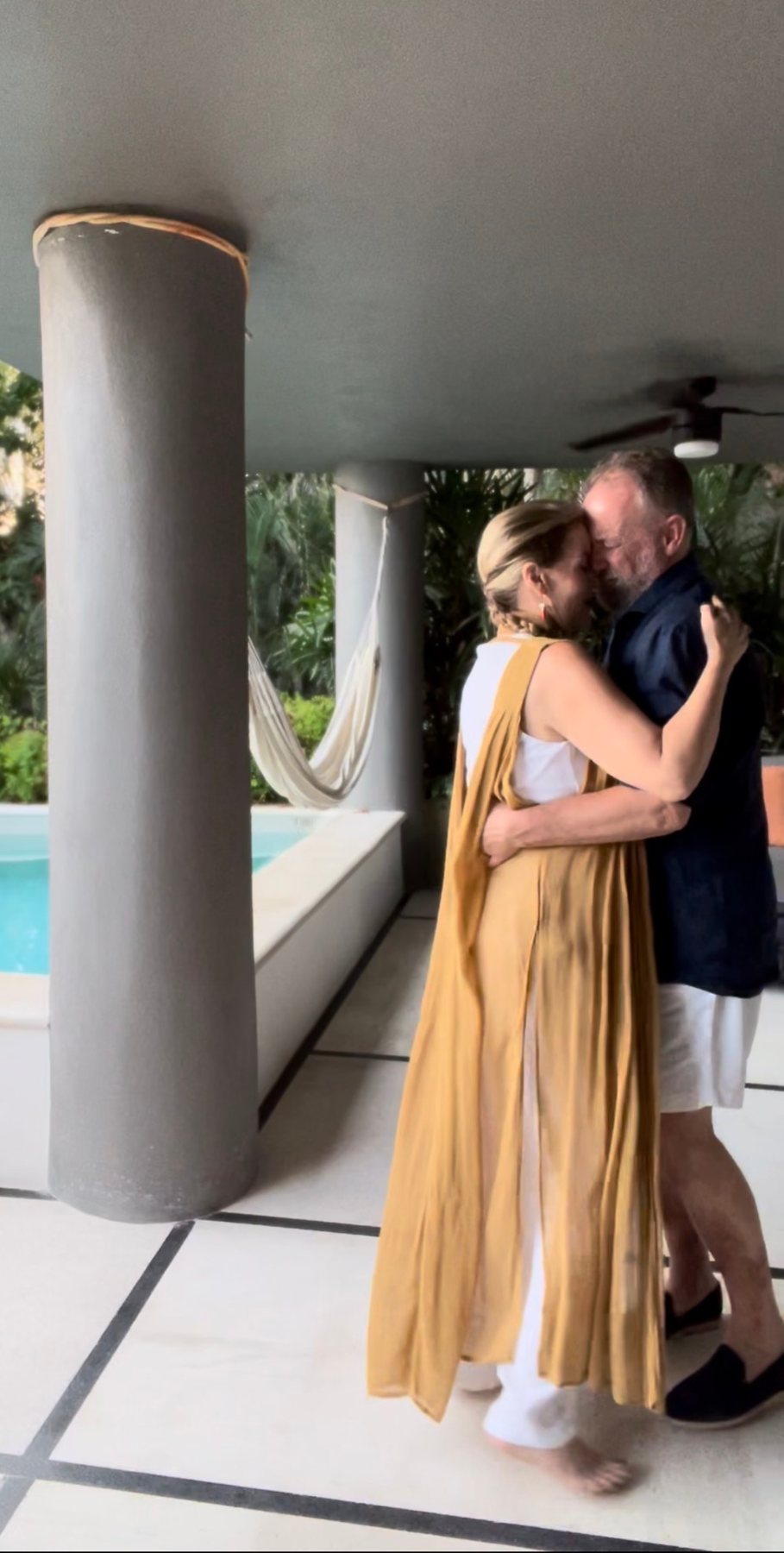 Juliette and Alex embracing on a covered terrace by a pool