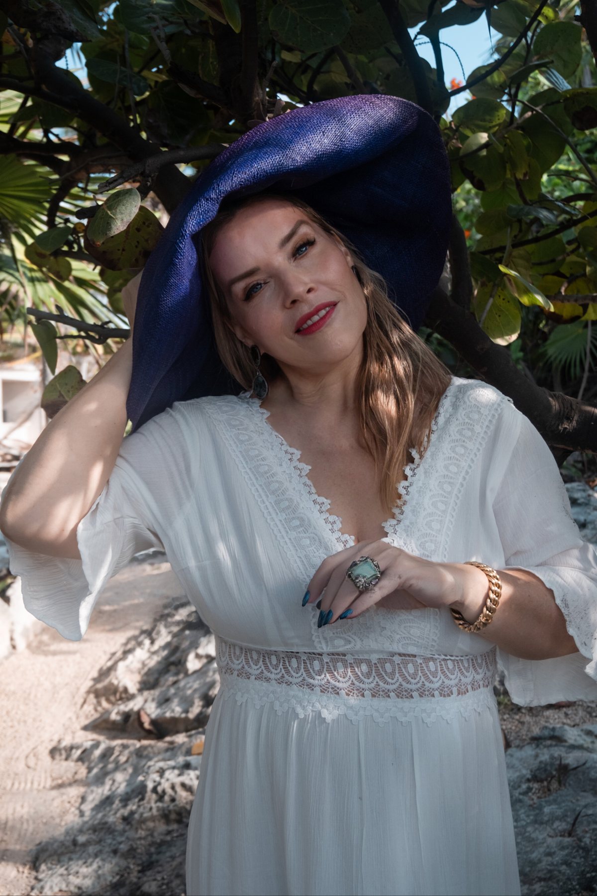 Juliette in a white dress and wide blue hat, smiling