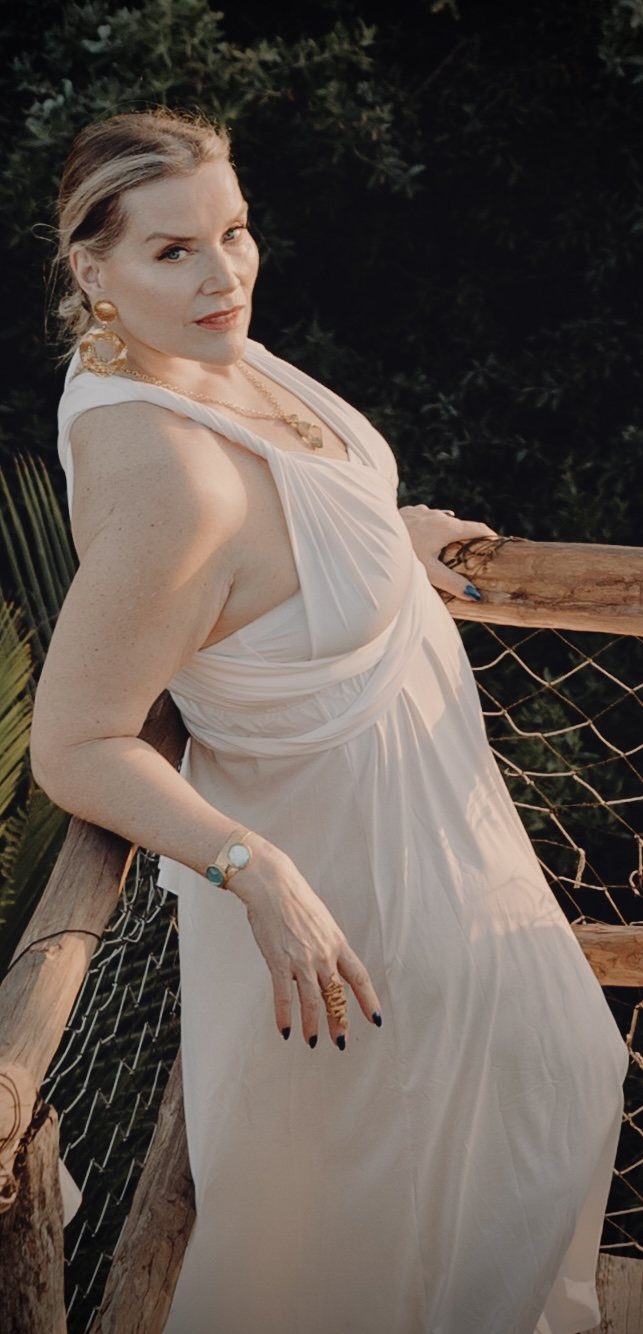 Juliette in a long white dress, standing by a wooden railing