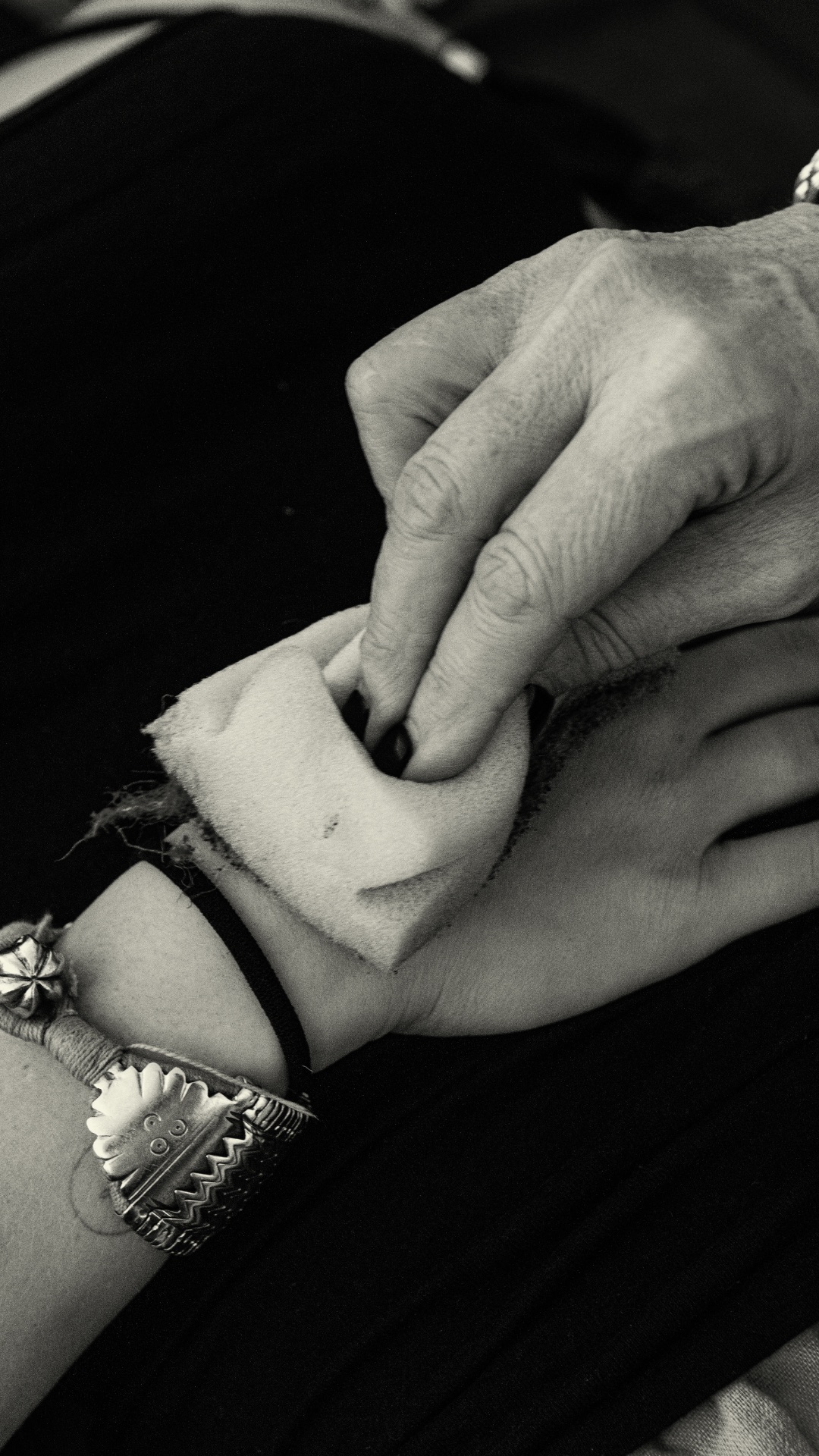 Black and white photo of one hand touching another wrist with a soft cloth